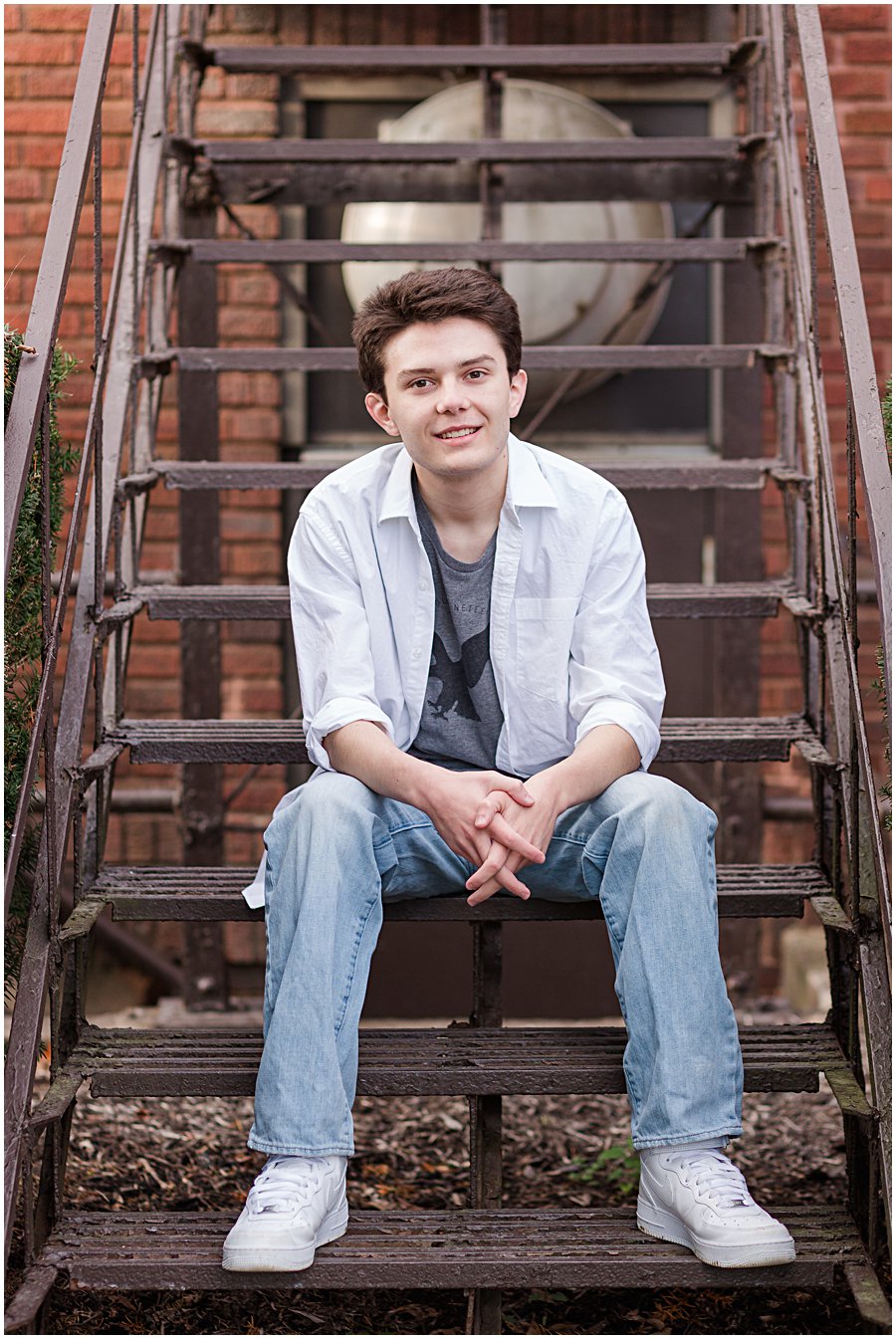 senior guy sitting on rustic steps at Holmesville Elementary, photographed by Jamie Lynette Photography