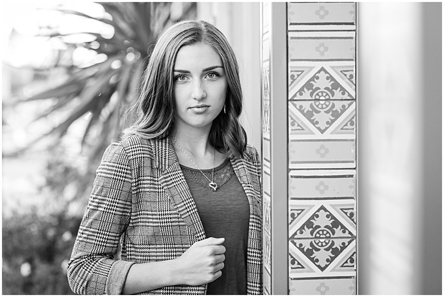 female high school senior standing next to Art Find Tile, with serious face, photo is black and white. 