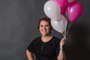 woman standing with grey backdrop behind her holding pink and white ballons!