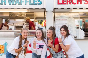 four high school senior girls holding a lerches donut up and smiling, photographed by Jamie Lynette Photography canton senior photographer