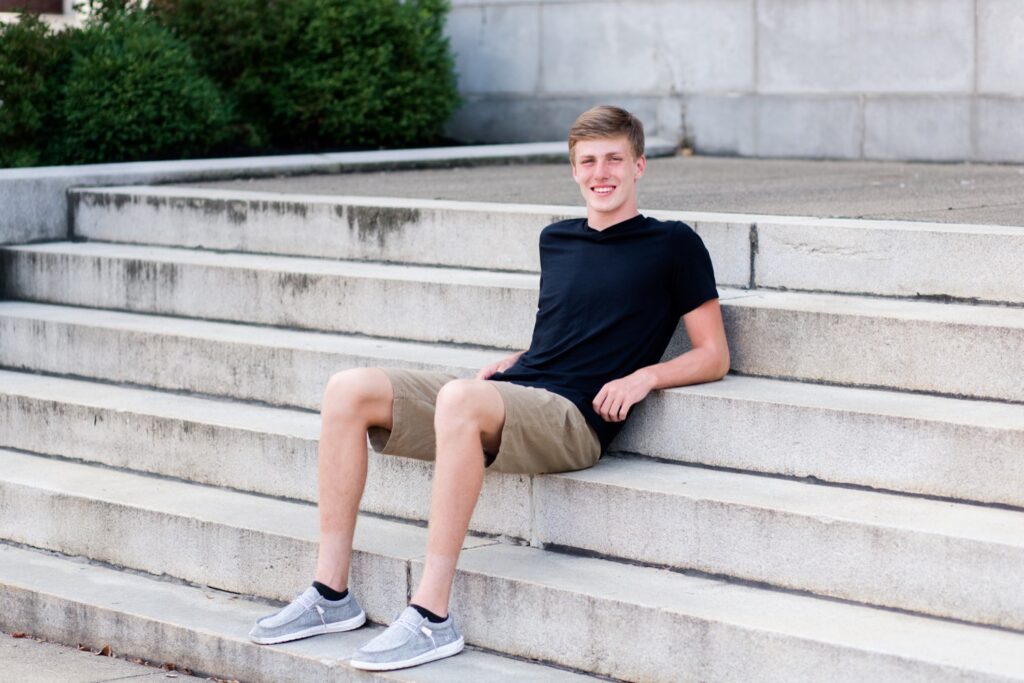 guy senior pictures on stone steps downtown Wooster.