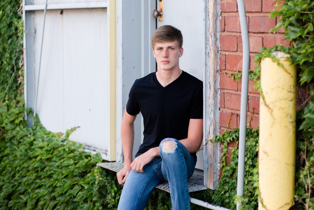 Urban senior photos downtown Wooster, guy senior pictures in front of ivy brick wall.