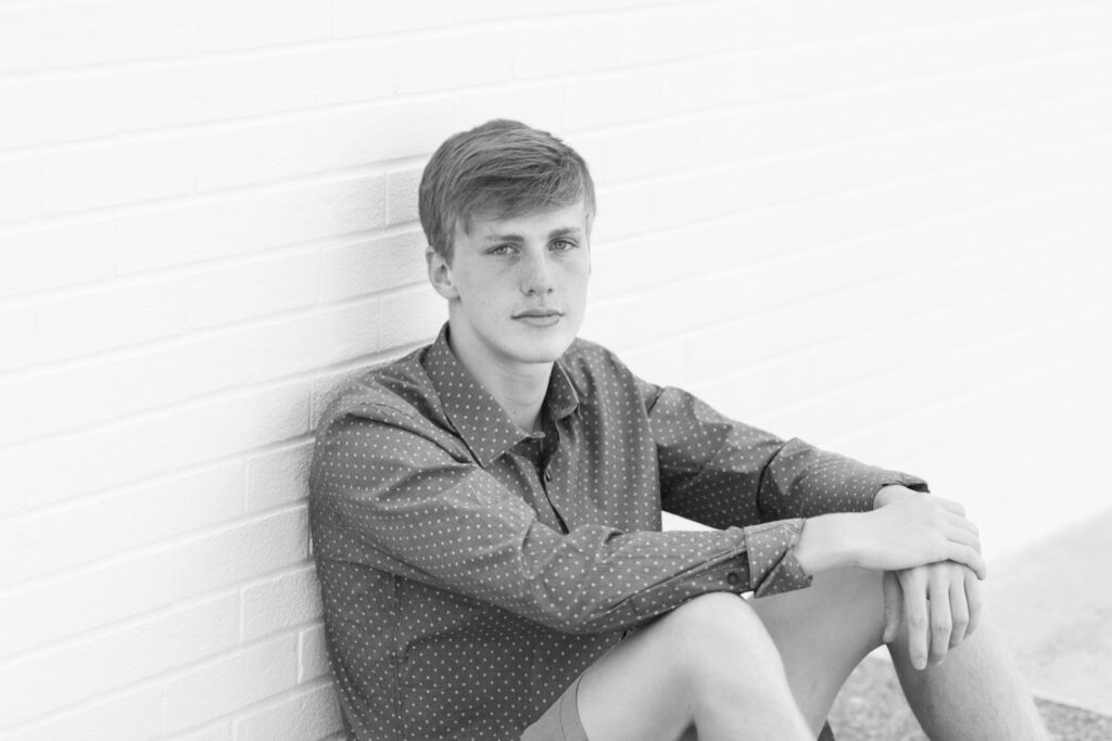 Urban senior photos downtown Wooster, guy senior pictures against a white brick wall.