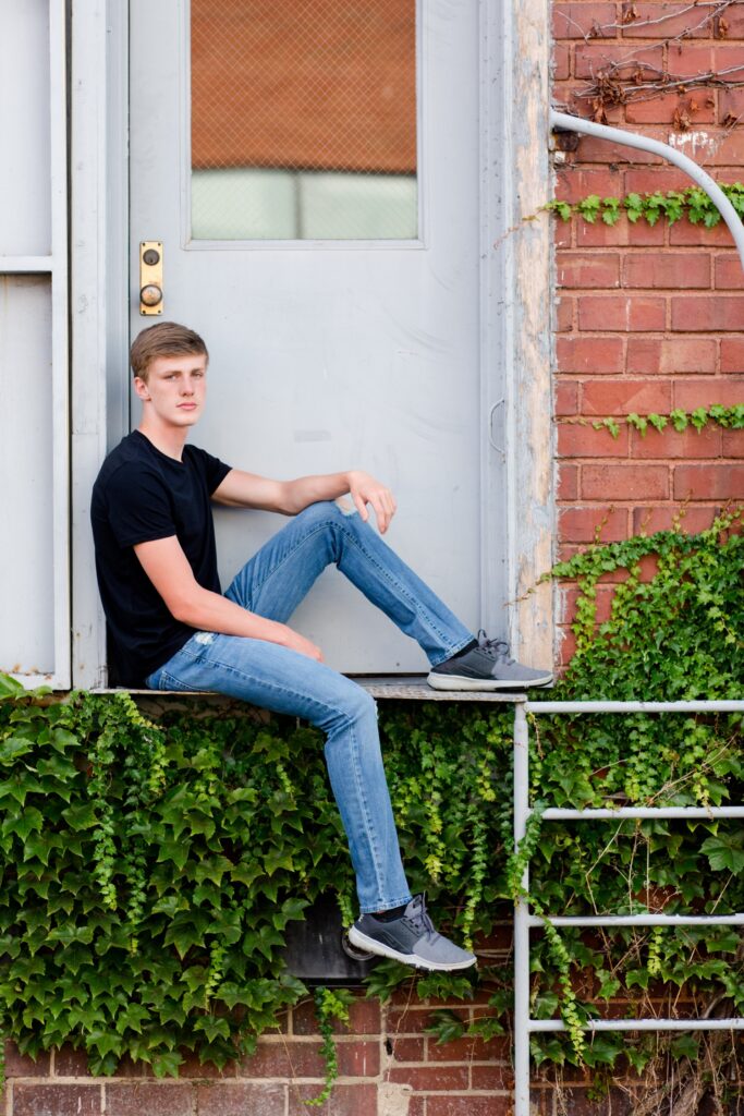 guy senior photos in front of ivy wall.