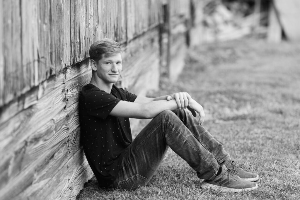 Senior boy sitting by barn, country boy session