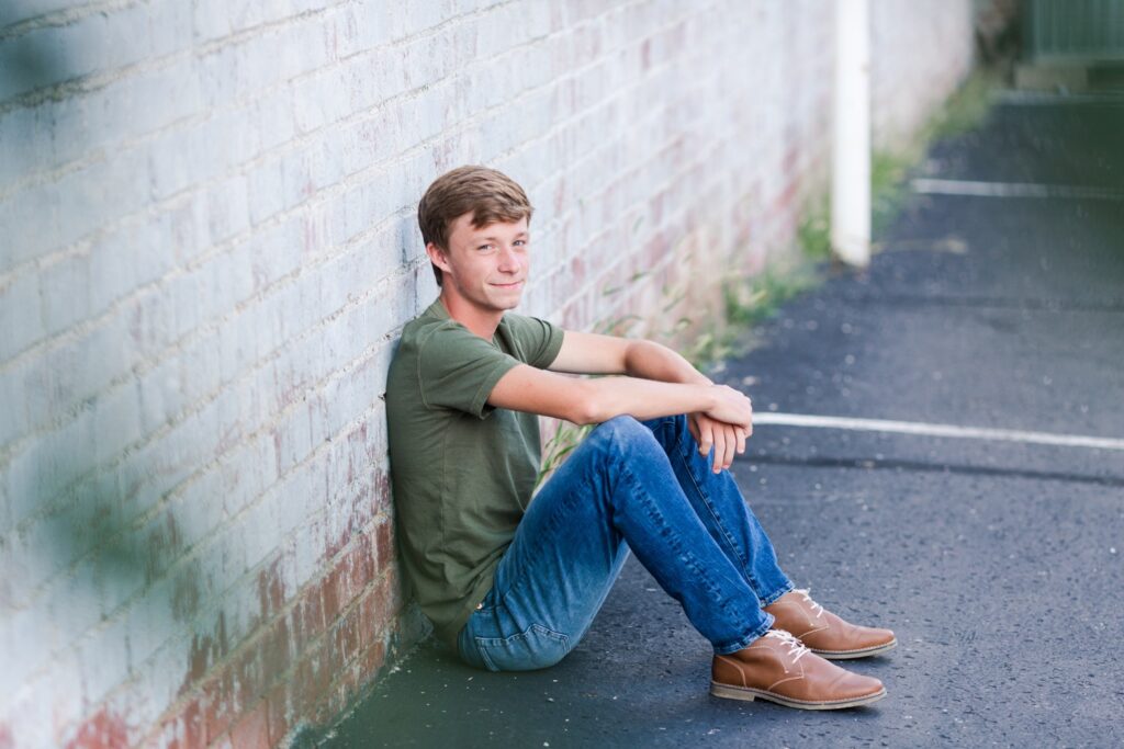 Senior guy leaning against brick wall