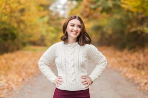 senior girl standing with lots of fall color behind her