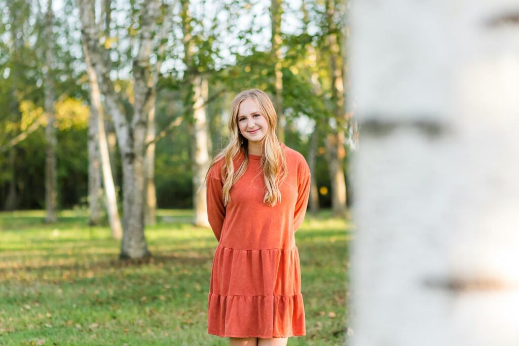 Fall with colorful setting with trees at the secrest arboretum, tall boots and an orange dress makes the photo pop.