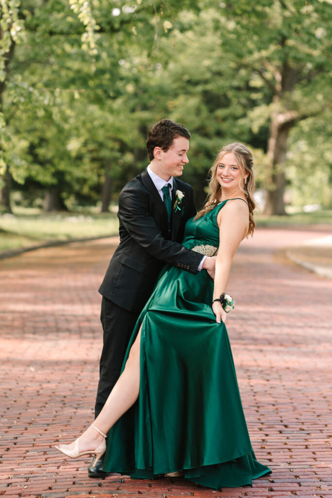 Prom couple in Wooster, Ohio, captured by Jamie Lynette Photography. The girl is wearing a green dress and the boy is in a black tux, sharing a joyful moment before prom. These are from their Prom Mini Session.