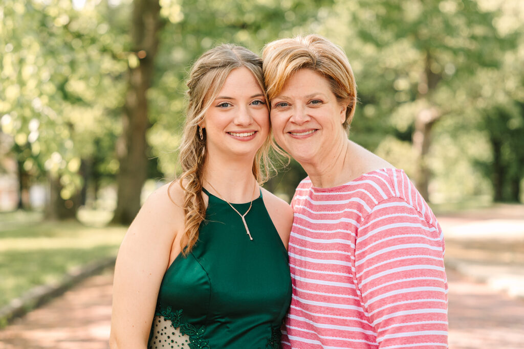 Senior girl dressed up for prom getting a photo with her Mom in Wooster, Ohio, captured by Jamie Lynette Photography. The girl is wearing a green dress and the boy is in a black tux, sharing a joyful moment before prom. These are from their Prom Mini Session.