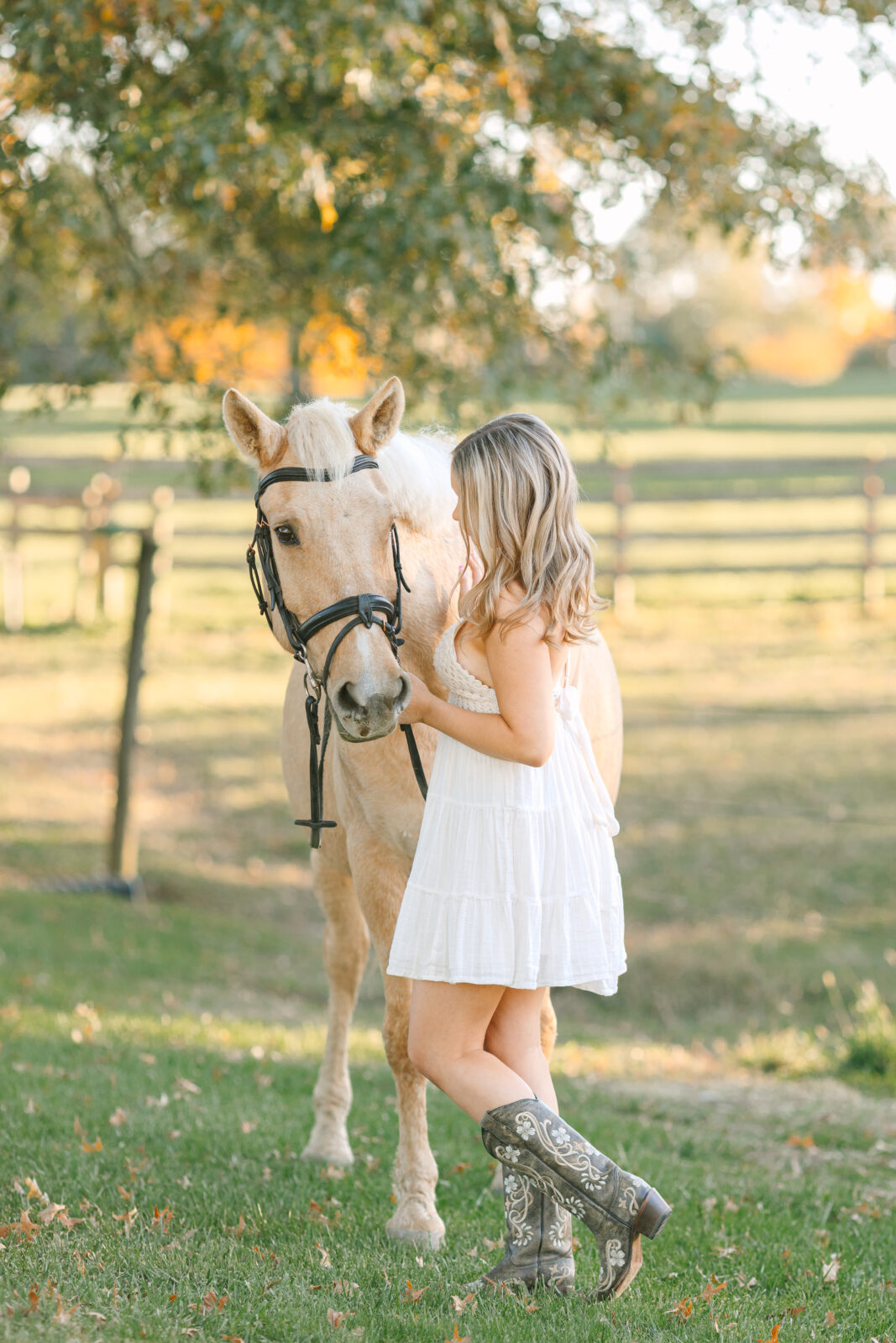 Equestrian senior pictures. Country-style senior photo of girl wearing lace dress and boots with her horse.